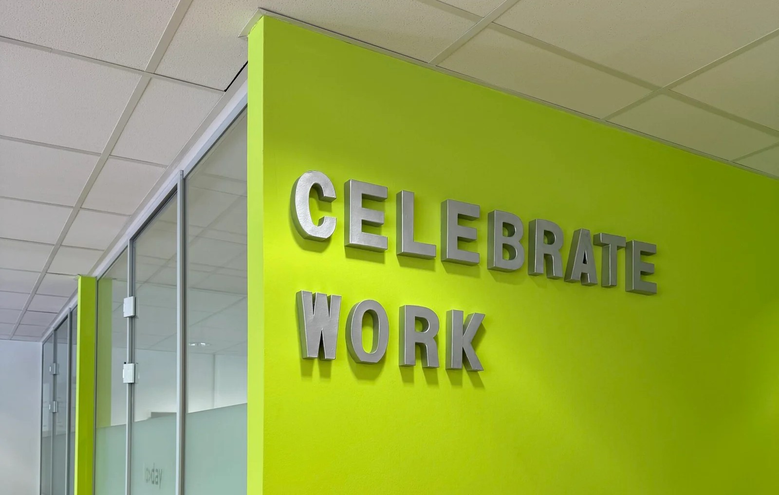 Besprechungsraum im Büro von TODAY Experts mit dem Wand-Schriftzug ‚Celebrate Work‘.“