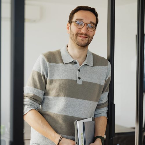Mitarbeiter von TODAY Experts steht zwischen Glastüren und schaut in die Kamera