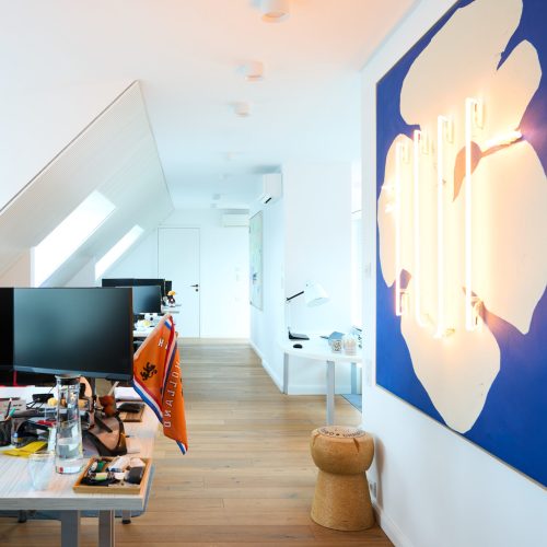 Arbeitsplätze in einem modernen Büro mit Kunst an den Wänden und hellem Flur“